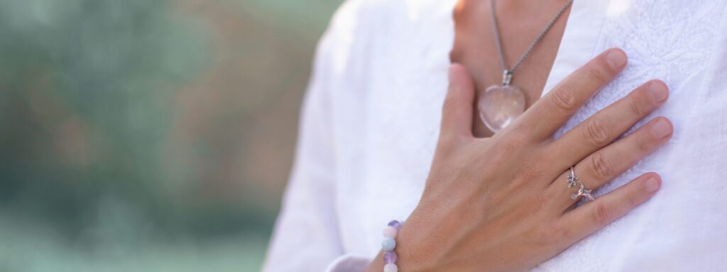 Een hand rust op de borst, boven een ketting met een hanger