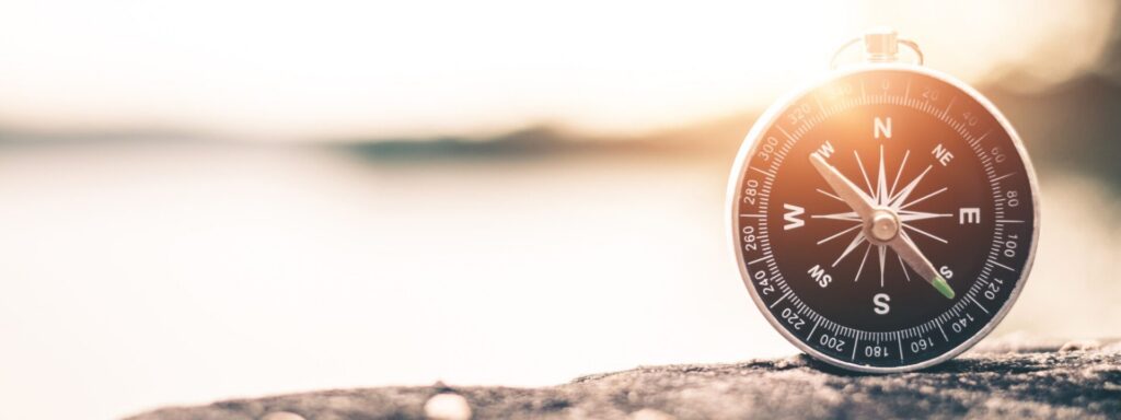 Een kompas op een steen aan het water in laag zonlicht