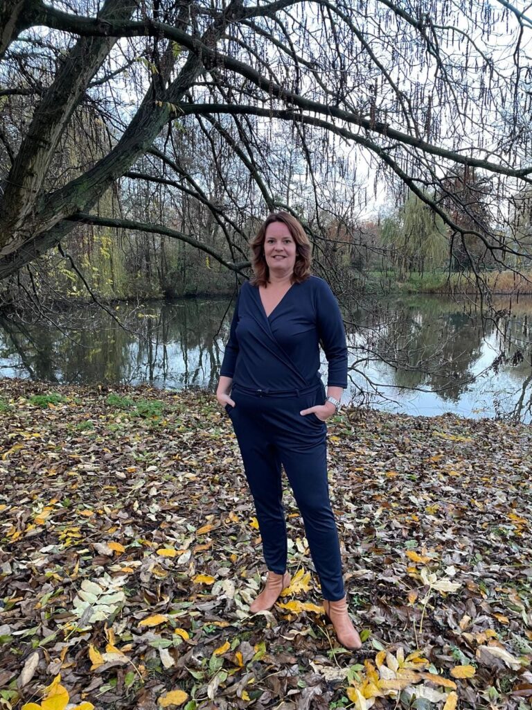 Petra van der Giessen staat tussen herfstbladeren aan het water